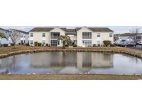 Exterior view of a condo building with a pond in front and a manicured lawn at 8830 Chandler Dr. # E, Myrtle Beach, SC 29575