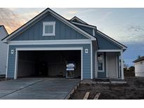 Newly constructed home with gray siding, two-car garage, and open driveway at 1241 Crested Iris Way, North Myrtle Beach, SC 29582