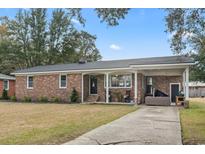Charming single-story brick home with a cozy front porch and covered parking area, set against a blue sky backdrop at 1673 Middleton St., Georgetown, SC 29440