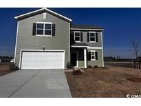 Charming two-story home with light green siding, white garage door, and a well-manicured front lawn at 677 Castillo Dr., Loris, SC 29569