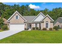 Charming brick home with a well-manicured lawn, attached garage, and inviting front entrance at 765 Ashley Manor Dr., Longs, SC 29568