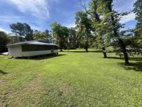Charming home with a screened porch nestled on a lush green lawn under a sunny sky at 1451 Cane Branch Rd., Loris, SC 29569