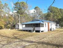Quaint, white home featuring a blue metal roof and screened porch at 1451 Cane Branch Rd., Loris, SC 29569