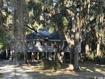 Elevated home with wrap-around porch and large shade trees at 187 Alston Rd., Pawleys Island, SC 29585