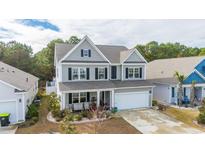Charming two-story home with gray siding, black shutters, a covered front porch and an attached garage at 405 Cypress Springs Way, Little River, SC 29566