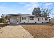 Charming single-story home featuring a brick exterior, dark trim, and a well-manicured front yard at 412 E Melrose St., Mullins, SC 29574