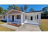 Charming brick home showcasing a welcoming porch and metal roof against a clear blue sky at 90 Wateree Trail, Georgetown, SC 29440