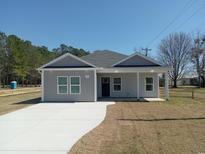 Charming gray home featuring a well-manicured lawn and a long, smooth driveway at 941 Hickman Rd., Tabor City, NC 28463