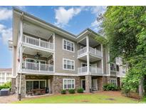 Multi-story condo featuring multiple balconies, stone accents, and outdoor seating area at 109 S Shore Blvd. # 104, Longs, SC 29568