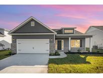 Gray house with white garage door and brick accents, landscaped lawn at 332 Hayloft Circle, Conway, SC 29526