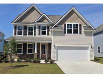 Inviting two-story home featuring a two-car garage, manicured lawn, and charming stone accents around the entryway at 550 Haven View Way, Murrells Inlet, SC 29576