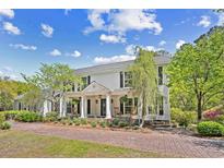 Charming two-story home with a welcoming front porch, rocking chairs, brick driveway and manicured landscaping at 356 Rossdhu Ave., Pawleys Island, SC 29585