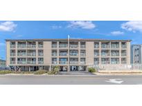 Three-story condo building with a beige facade and balconies under a blue sky at 4303 N Ocean Blvd. # C2, North Myrtle Beach, SC 29582