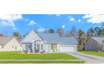 Gray house with blue roof, white garage door, and landscaped lawn at 451 Cypress View Ave., Little River, SC 29566