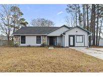 Charming single-Gathering home featuring stone accents, a gray siding exterior, and a well-manicured lawn at 232 Stonebridge Dr., Myrtle Beach, SC 29588