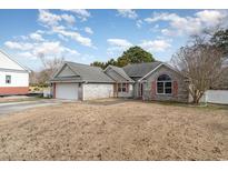 Brick ranch home with attached garage and landscaped yard at 424 Meadow View Ct., Longs, SC 29568