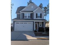 Two-story house with gray siding, white garage door, and landscaping at 740 Hackberry Way, Longs, SC 29568