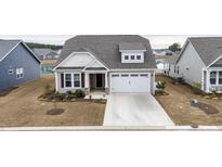 Beige two-story house with a gray roof, white garage door, and landscaping at 1262 Witch Hazel Way, Longs, SC 29568