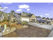 Tan two-story house with a two-car garage and landscaped yard at 1552 Jardine Loop, Little River, SC 29566