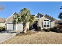 Beige two-story house with two-car garage and palm tree in front at 3006 Winding River Rd., North Myrtle Beach, SC 29582