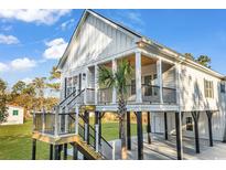 Charming elevated beach house with black railings, wooden stairs and a well maintained lawn and palm tree at 33 Captains Pl, Murrells Inlet, SC 29576