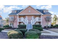 Two-story condo building with light peach exterior, balconies, and manicured landscaping at 4650 Lightkeepers Way # 21D, Little River, SC 29566