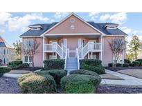 Two-story condo building with light peach exterior, stairs, and landscaping at 4650 Lightkeepers Way # 21D, Little River, SC 29566