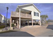 Elevated beach home with deck, parking underneath, and nicely landscaped yard at 9620 Windchime Dr., Myrtle Beach, SC 29572