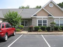 Charming single-story home with brick accents, manicured landscaping and a red SUV in the parking area at 4672 Lightkeepers Way # 50-E, Little River, SC 29566