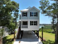 Charming raised beach home featuring a two-story design, blue siding, and classic black shutters at 48 Furman Ln., Pawleys Island, SC 29585