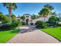 Luxury home with brick driveway, lush landscaping, and palm trees at 500 Posada Dr., Myrtle Beach, SC 29572