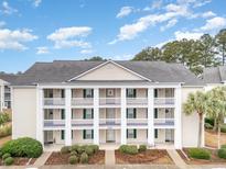 Two-story condo building with light beige exterior, white columns, and balconies at 5010 Windsor Green Way # 301, Myrtle Beach, SC 29579