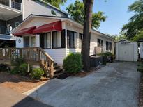 Charming home with red awning, wooden deck, driveway, and manicured bushes at 6001-Z16 S Kings Hwy., Myrtle Beach, SC 29575
