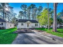 White house with green trim and landscaping, driveway, and trees at 6633 W Sweetbriar Trail, Myrtle Beach, SC 29588