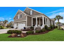 Charming two-story home featuring a three-car garage, manicured lawn, and inviting front porch with stately columns at 7000 Legare Pl., Myrtle Beach, SC 29579