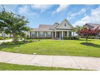 Charming single-Gathering home featuring a well-manicured lawn, lush landscaping, and a welcoming front porch with columns at 1405 Osprey Pointe Ln., North Myrtle Beach, SC 29582