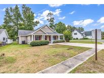 Charming single-story home featuring a cozy front porch, manicured lawn and mature landscaping at 1900 Shell Ct., Surfside Beach, SC 29575