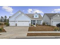 Two-story house with light blue siding, three-car garage, and manicured lawn at 2659 Blue Crane Circle, Myrtle Beach, SC 29577