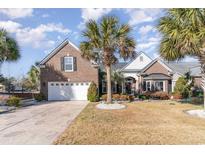 Brick home with palm trees, landscaped yard, and a three-car garage at 4608 Grovecrest Circle, North Myrtle Beach, SC 29582