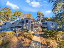 Gray condo building with multiple units, surrounded by lush landscaping at 88 Salt Marsh Circle # 22H, Pawleys Island, SC 29585