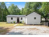 White house with black accents, a gravel driveway, and a fenced backyard at 9719 E Highway 76, Nichols, SC 29581