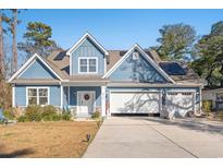Two-story house with blue siding, a three-car garage, and a well-manicured lawn at 816 17Th Ave. N, Surfside Beach, SC 29575