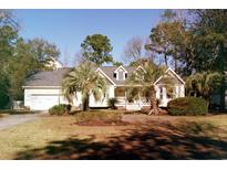 Charming one-story home with a two-car garage, inviting porch, and beautiful palm trees in the front yard at 390 Crooked Oak Dr., Pawleys Island, SC 29585