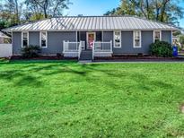 Gray house with metal roof, white porch, and green lawn at 619 5Th Ave. N, Surfside Beach, SC 29575