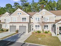 Tan siding two-story townhome with two-car garage and landscaping at 100 Machrie Loop # 17-C, Myrtle Beach, SC 29588