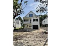 Charming exterior of elevated home with black garage door and white siding and black window trim at 1718 26Th Ave. N, North Myrtle Beach, SC 29582