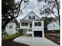 Charming two-story coastal home with black shutters, a covered porch and a driveway leading to a garage at 1718 26Th Ave. N, North Myrtle Beach, SC 29582
