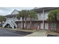 A two-story building with brick facade, palm trees, and white staircases leading to the second floor at 241 Presidential Dr., Surfside Beach, SC 29575