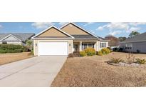 Beige house with white garage door, landscaping, and driveway at 242 Sienna Dr., Little River, SC 29566