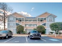 Three-story building exterior with light blue siding, peach accents, and ample parking at 4637 Lightkeepers Way # 4F, Little River, SC 29566